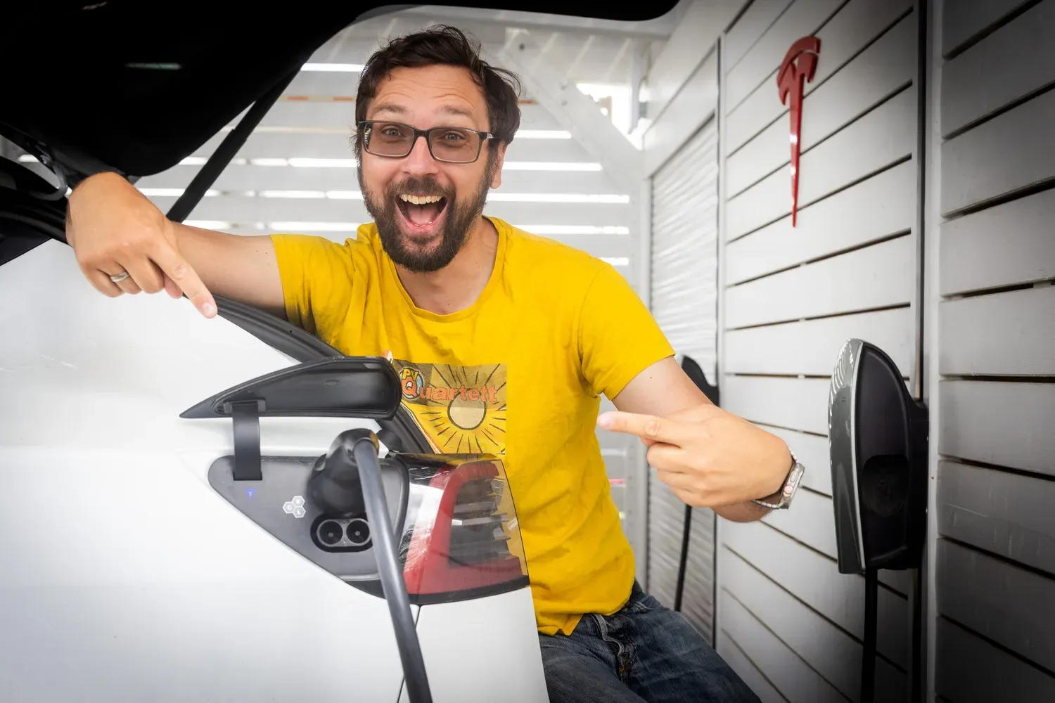 Jörg am offenen Ladeport seines Teslas vor dem Tesla Wall Connector