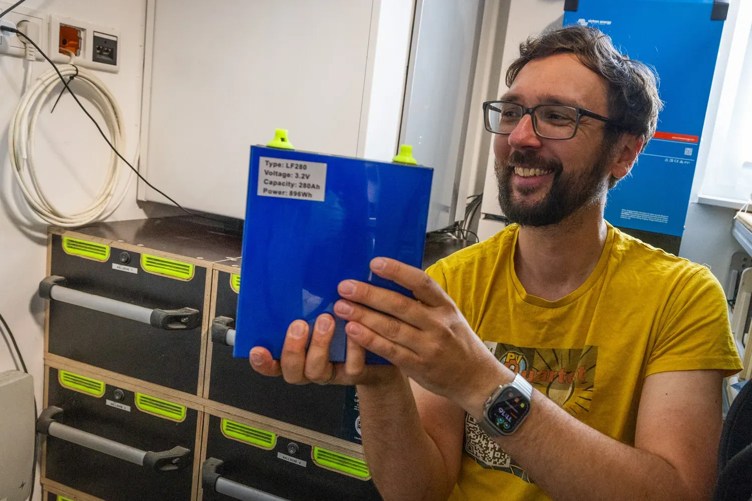 Jörg mit einer LFP-Zelle vor seinem DIY-Speicher
