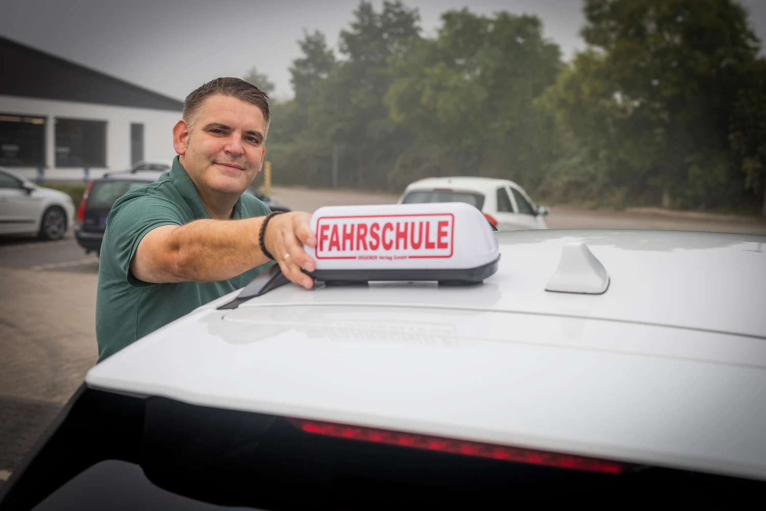 Alex am Fahrschulschild auf dem Autodach
