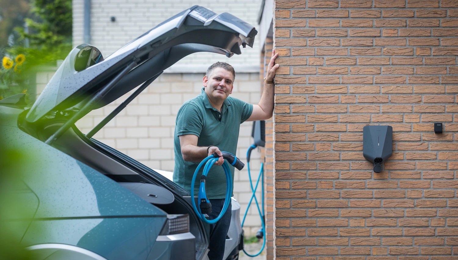 Alex mit Ladekabel vor zwei Wallboxen